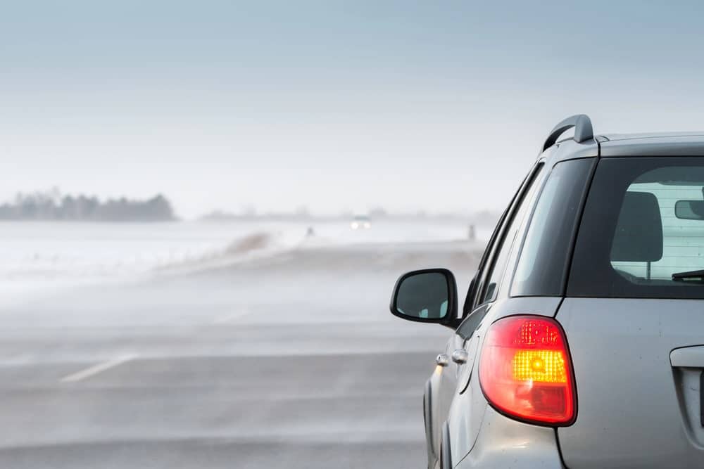 ehicle driving carefully on a foggy road with low visibility.