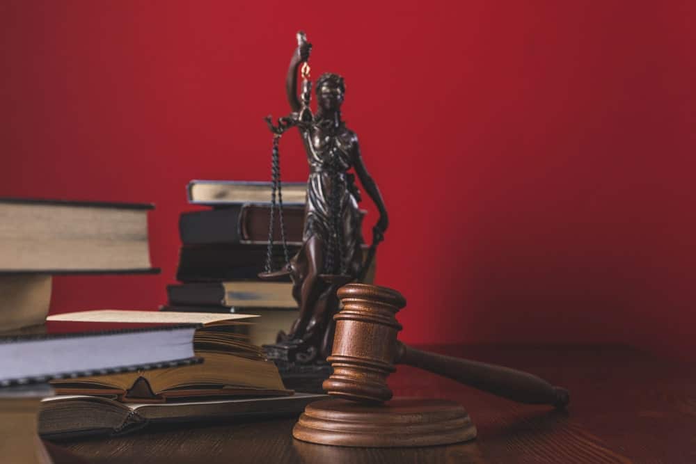 Image shows law books, a wooden gavel, and a Lady Justice statue on a desk, symbolizing legal rights and compensation issues after a motorcycle accident.
