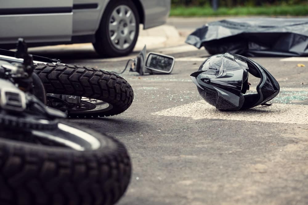 Image is of a damaged motorcycle helmet and debris on the road, highlighting the severe impact often seen in motorcycle accidents in TN