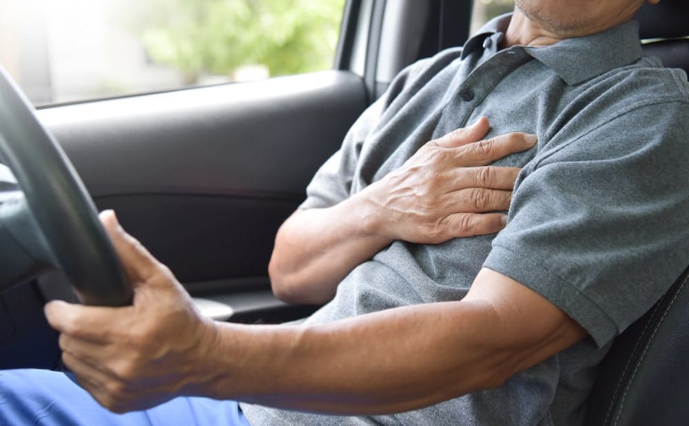 Image is of a driver holding his chest while seated in a vehicle, showing potential internal injuries commonly linked to truck crashes in Tennessee