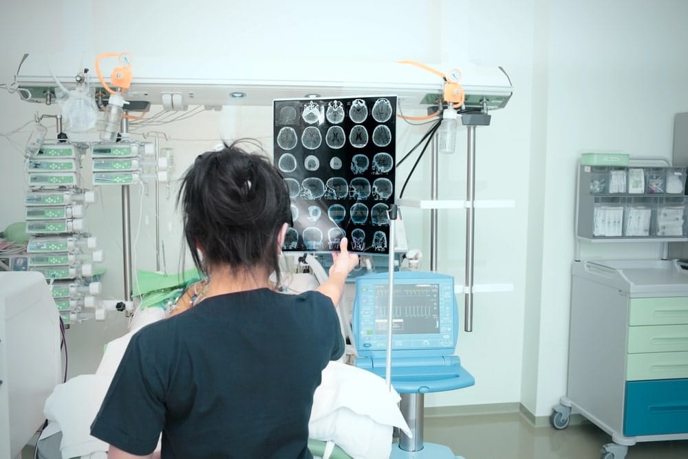 Image is of a medical professional reviewing brain scan images in a hospital setting, highlighting head trauma injuries caused by truck crashes in Tennessee