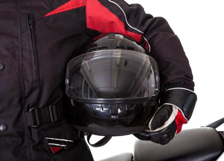 Image is of a motorcyclist holding a protective helmet, illustrating how Tennessee helmet laws influence safety expectations and claim evaluations.