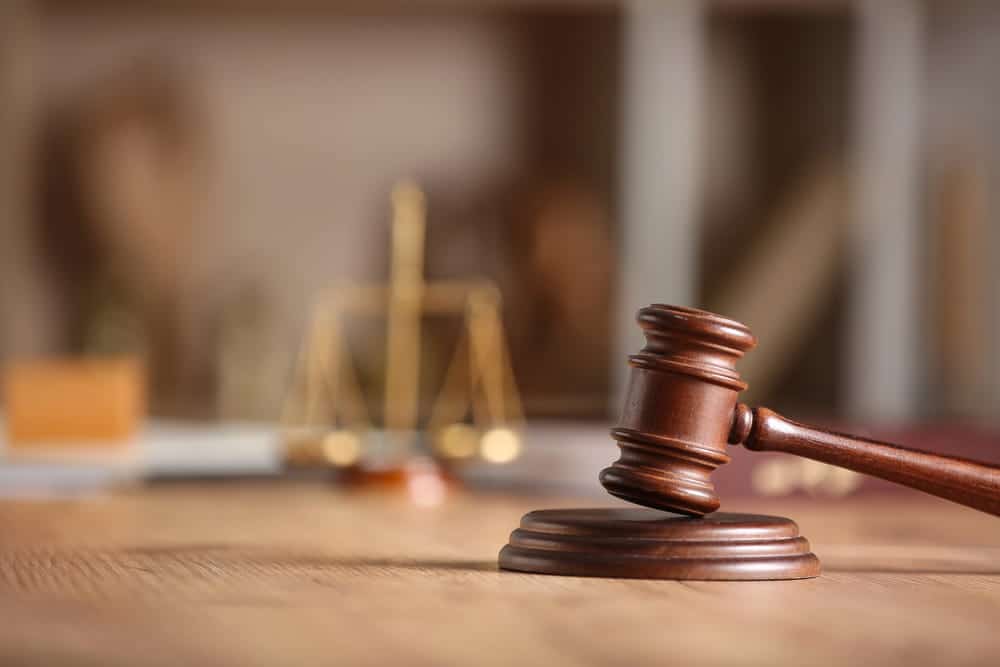 Image is of a courtroom gavel with justice scales in the background, concept of legal responsibility in a motorcycle crash case.