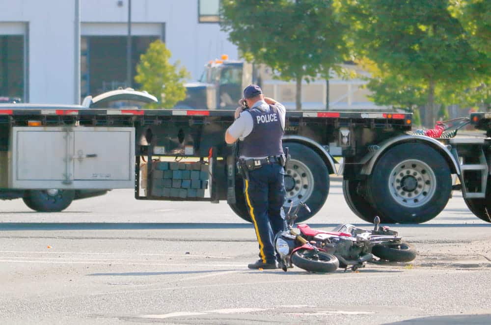 Image is of a police officer documenting a motorcycle crash scene involving a truck, concept of car accidents in Murfreesboro and on scene investigation.