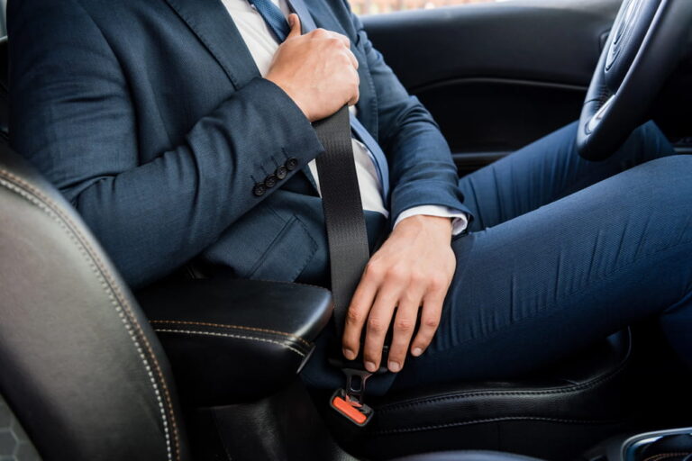 Image is of a driver fastening a seatbelt inside a vehicle, concept of injury claims in Tennessee and safety compliance considerations