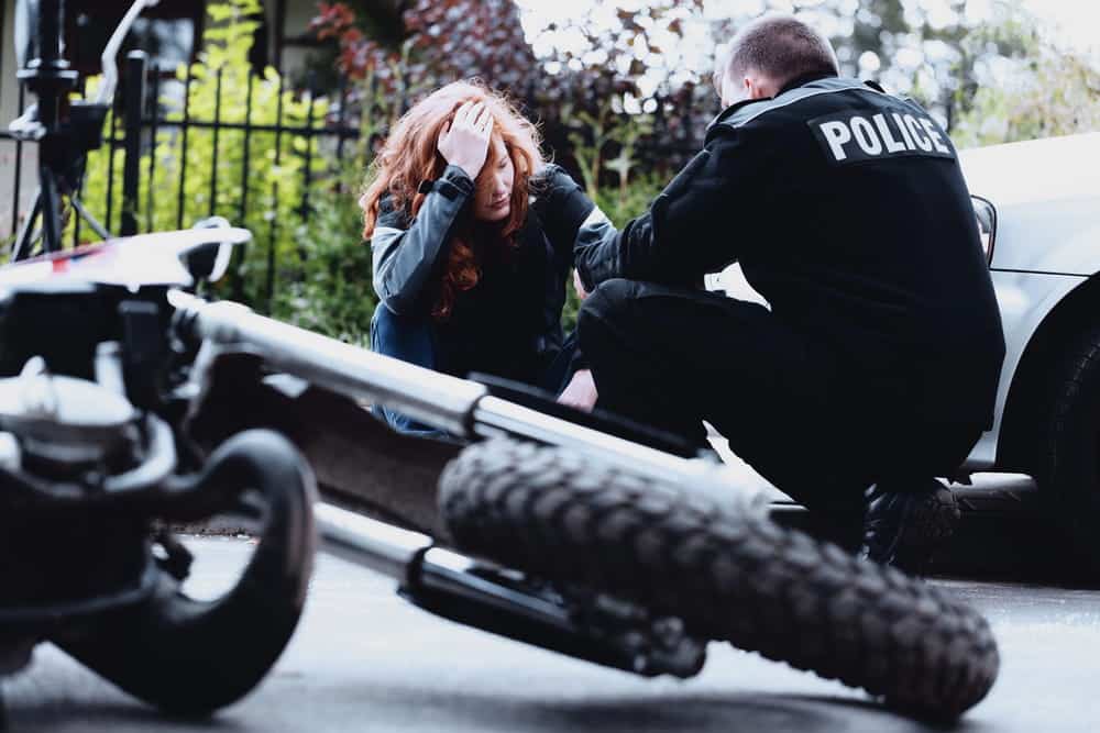 Image is of a police officer assisting an injured woman after a motorcycle accident in TN, highlighting emergency response following a hit and run crash.