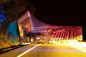 Image is of an overturned semi truck blocking the road at night, showing a Jackknife Truck accident in Murfreesboro