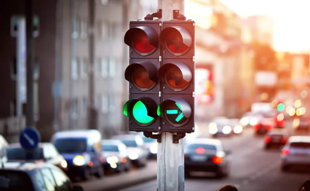 Image shows a traffic signal at a busy city intersection with vehicles approaching from multiple directions, illustrating how traffic signals relate to intersection accidents in Murfreesboro.