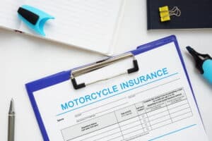 Image is of a motorcycle insurance application on a blue clipboard with a pen, concept of filing a motorcycle accident report.