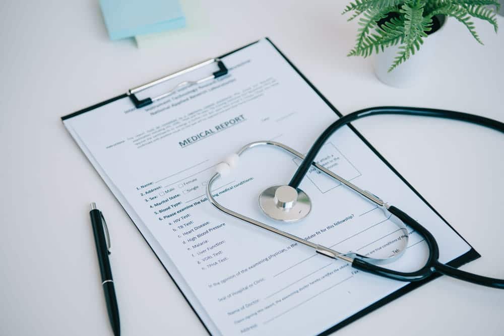 Image is of a medical report with a stethoscope placed on top, representing injury documentation in a motorcycle accident claim