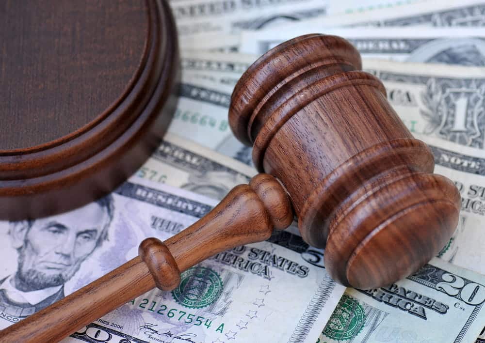 Image is of a gavel placed over cash, concept of car sccident settlements and financial compensation evaluation