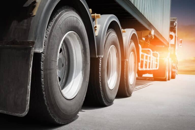 Image is of a semi truck traveling on a highway, showing tire condition and how poor upkeep can increase the risk of truck accidents.