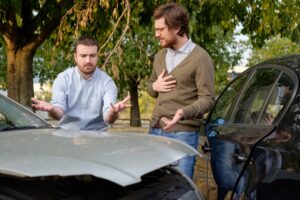 Image is of drivers discussing responsibility after a roadway collision, concept of car accident investigation.