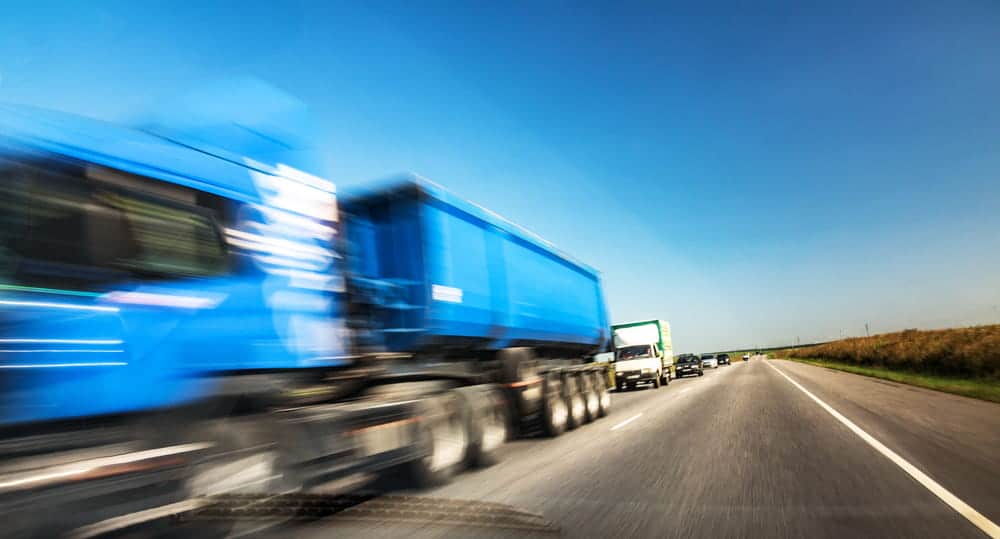 Image is of a commercial truck traveling at high speed along a highway, concept of a truck accident caused by speeding in Tennessee.