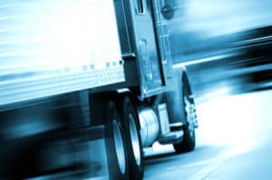 Image is of a semi truck in motion with visible speed blur, concept of a truck accident resulting from excessive speed and reduced reaction time.