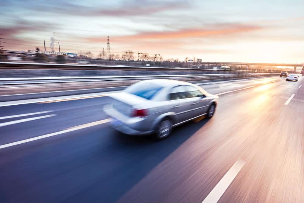 Image is of a vehicle traveling at high speed on a roadway, concept of a car accident involving teen drivers and speeding behavior.