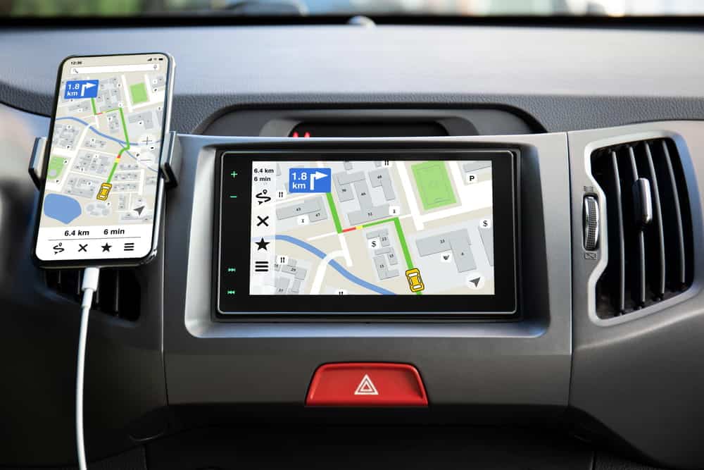 Image is of a vehicle navigation screen and smartphone, concept of distracted driving caused by in vehicle technology.