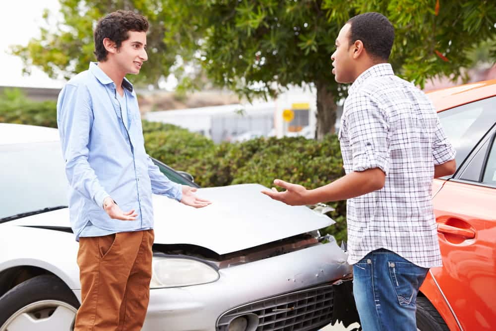Image is of two drivers discussing responsibility after a vehicle collision, concept of fault in Tennessee.