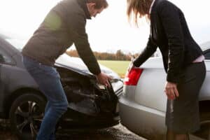 Image is of two drivers inspecting vehicle damage after a crash, concept of fault in Tennessee.