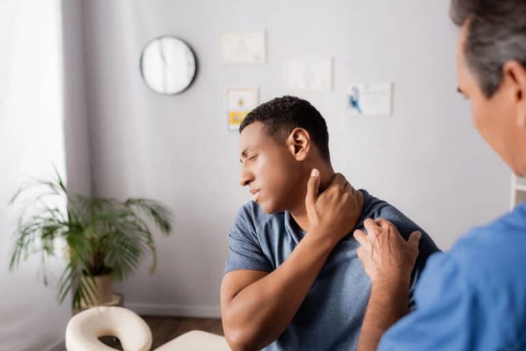 Image is of a man experiencing neck pain during a medical evaluation, concept of delayed pain after a motorcycle accident
