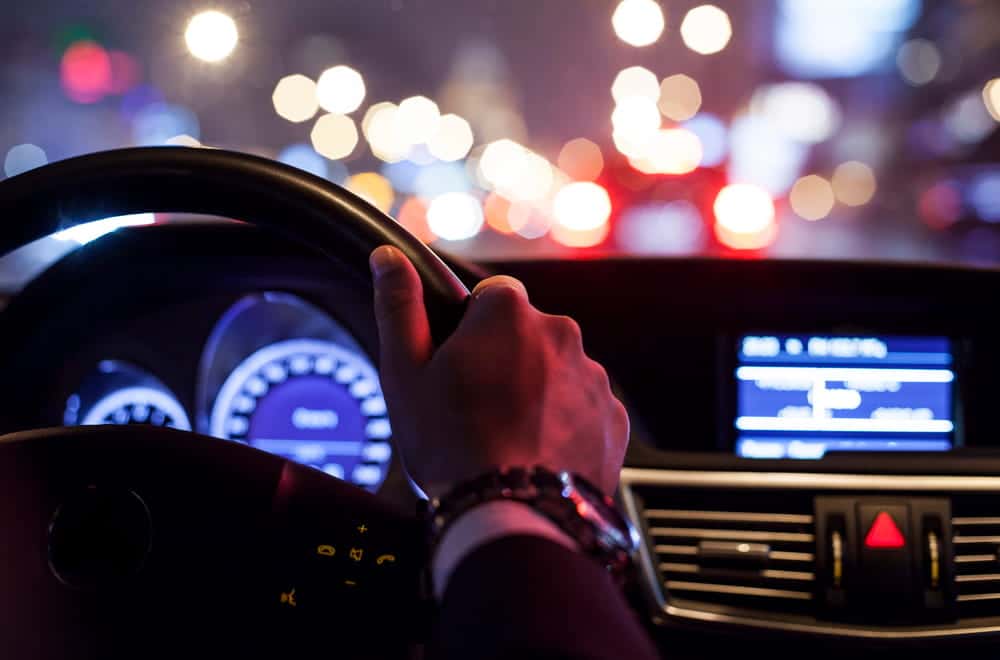 Image is of a driver holding the steering wheel at night in heavy traffic, concept of holiday driving risks in Murfreesboro.