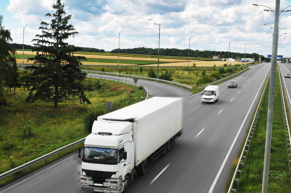 Image is of a semi truck traveling on a highway, concept of truck blind spot risks and crash liability