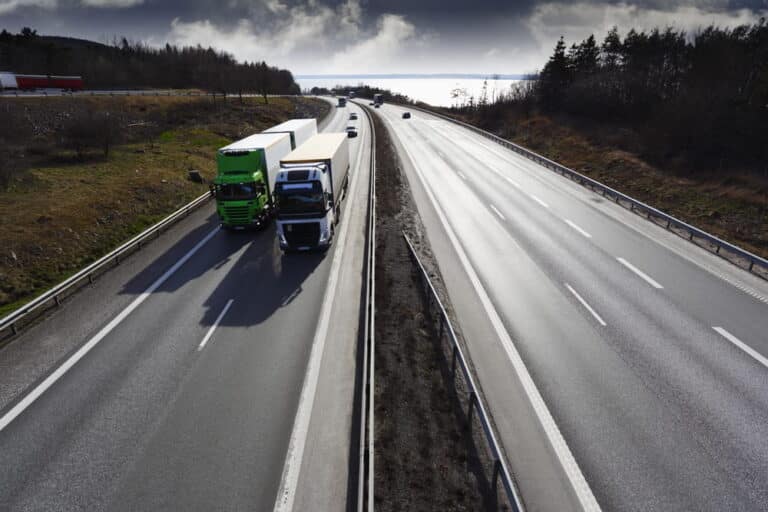 Image is of semi trucks traveling in adjacent interstate lanes, concept of truck blind spot dangers in Tennessee crashes