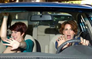Image is of a driver and passenger reacting inside a vehicle, concept of passengers who sue after a car accident.