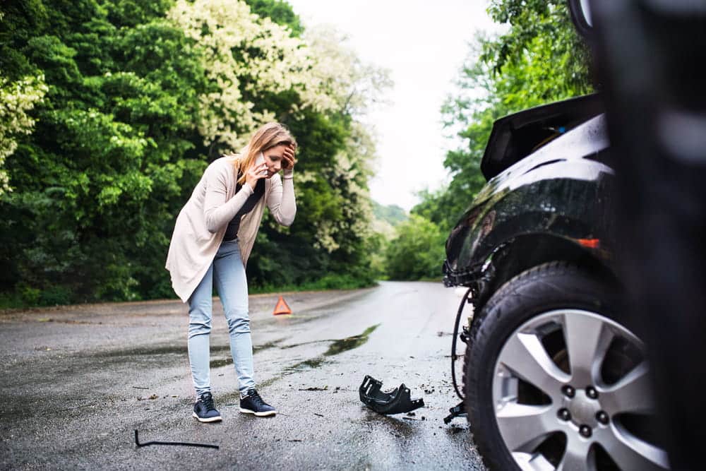 Image is of a driver calling for help beside a damaged vehicle, concept of documenting a car accident in TN.