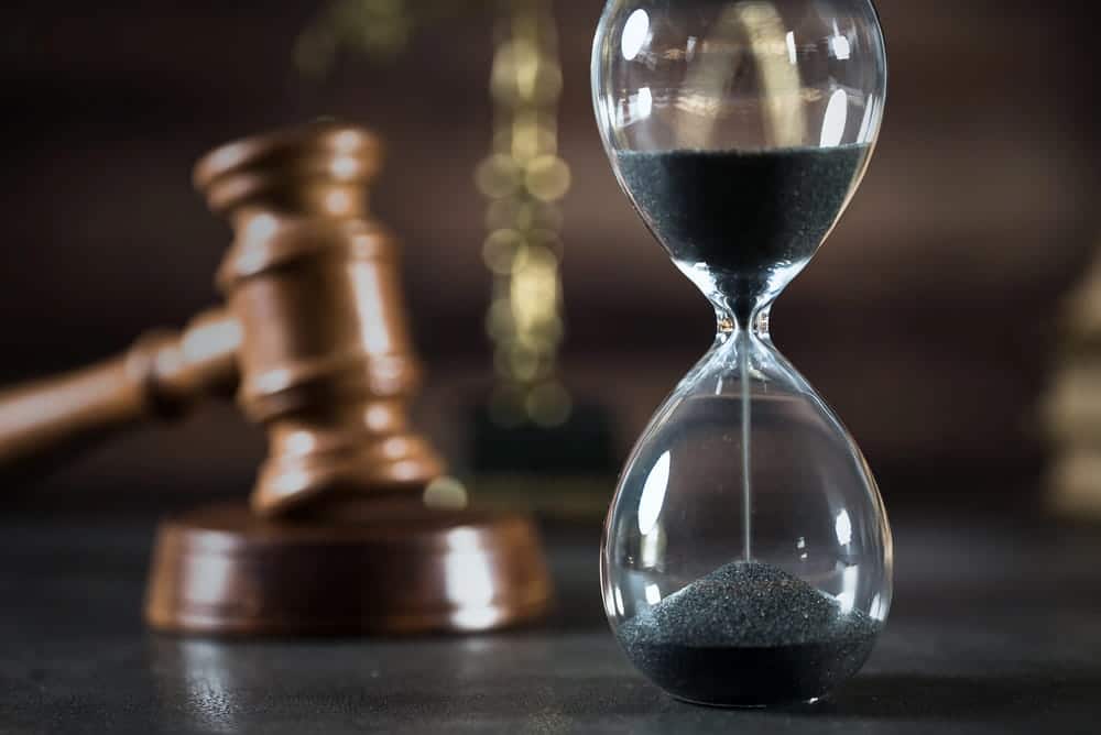 Image is of a black sand hourglass standing beside a wooden judge's gavel, concept of time limits for filing a car accident claim in Tennessee.