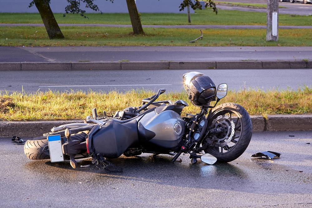 Image is of a damaged motorcycle lying on a wet road, concept of weather contributing to motorcycle accidents in TN.