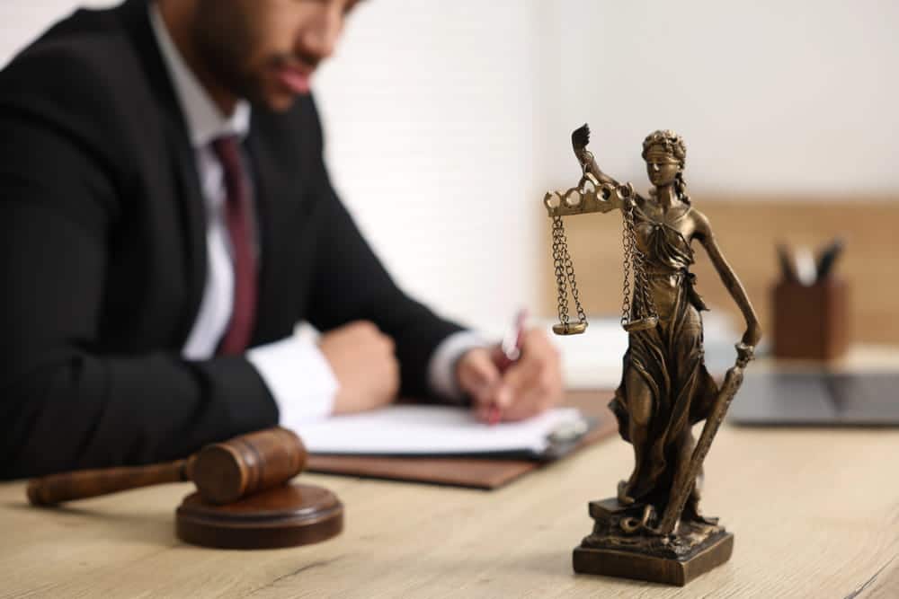 Image is of a lawyer reviewing legal documents beside a gavel and Lady Justice statue, concept of legal representation after a truck accident in TN.